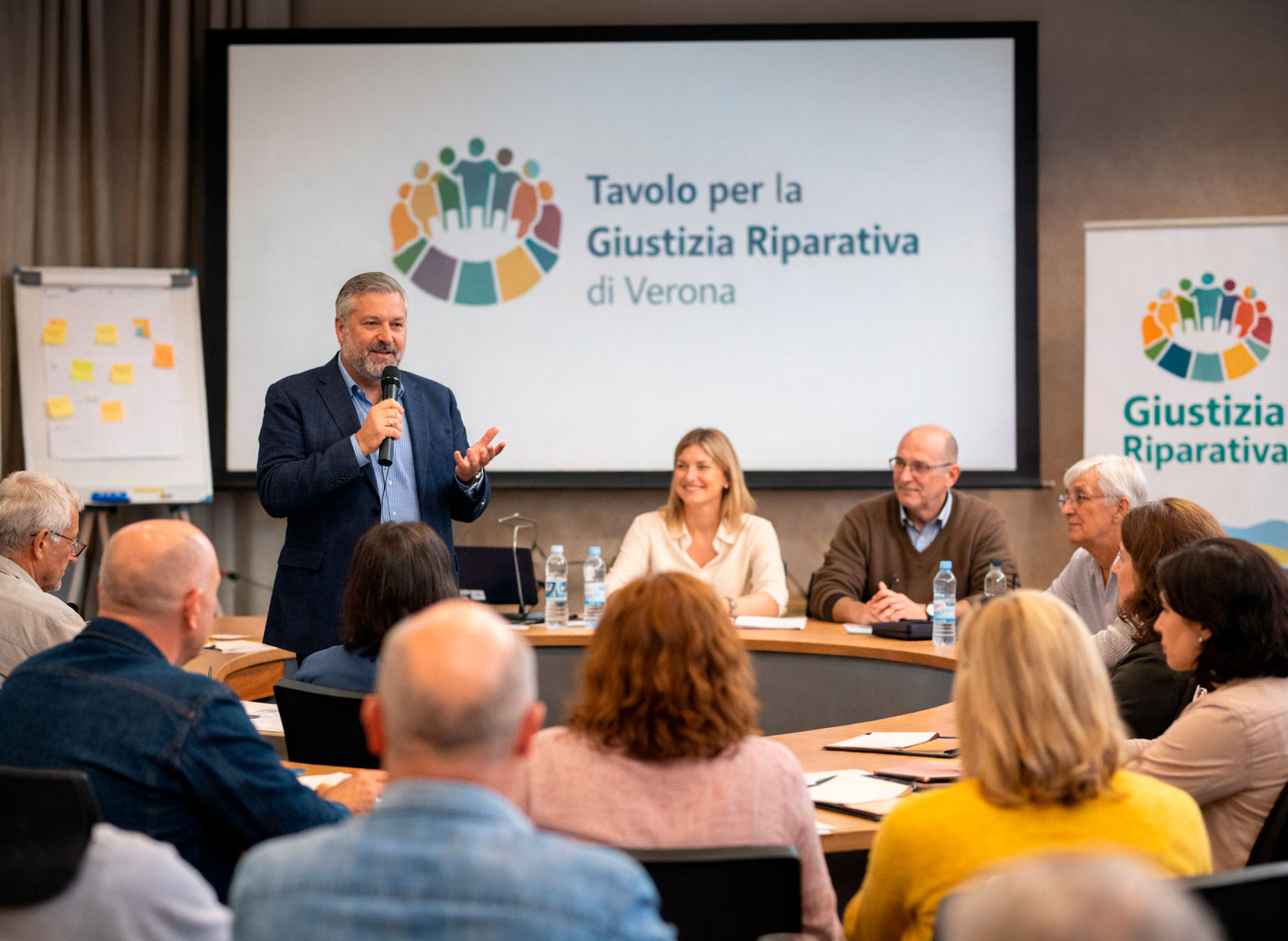 Incontro pubblico sulla giustizia riparativa a Verona con relatori e partecipanti riuniti attorno a un tavolo durante una conferenza